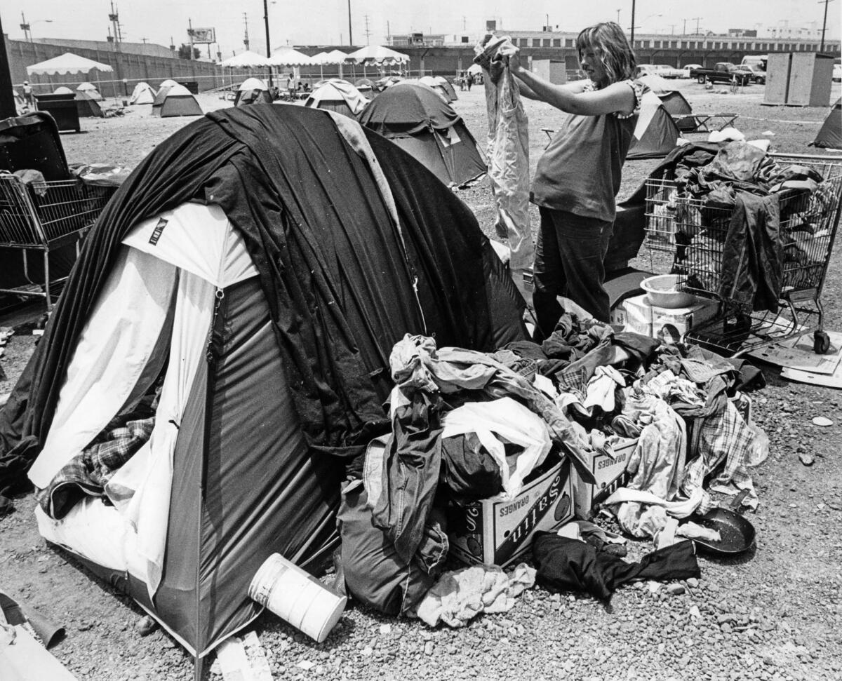 June 26, 1987: Lisa Gillie, 7 months' pregnant, sorts clothes outside her tent.