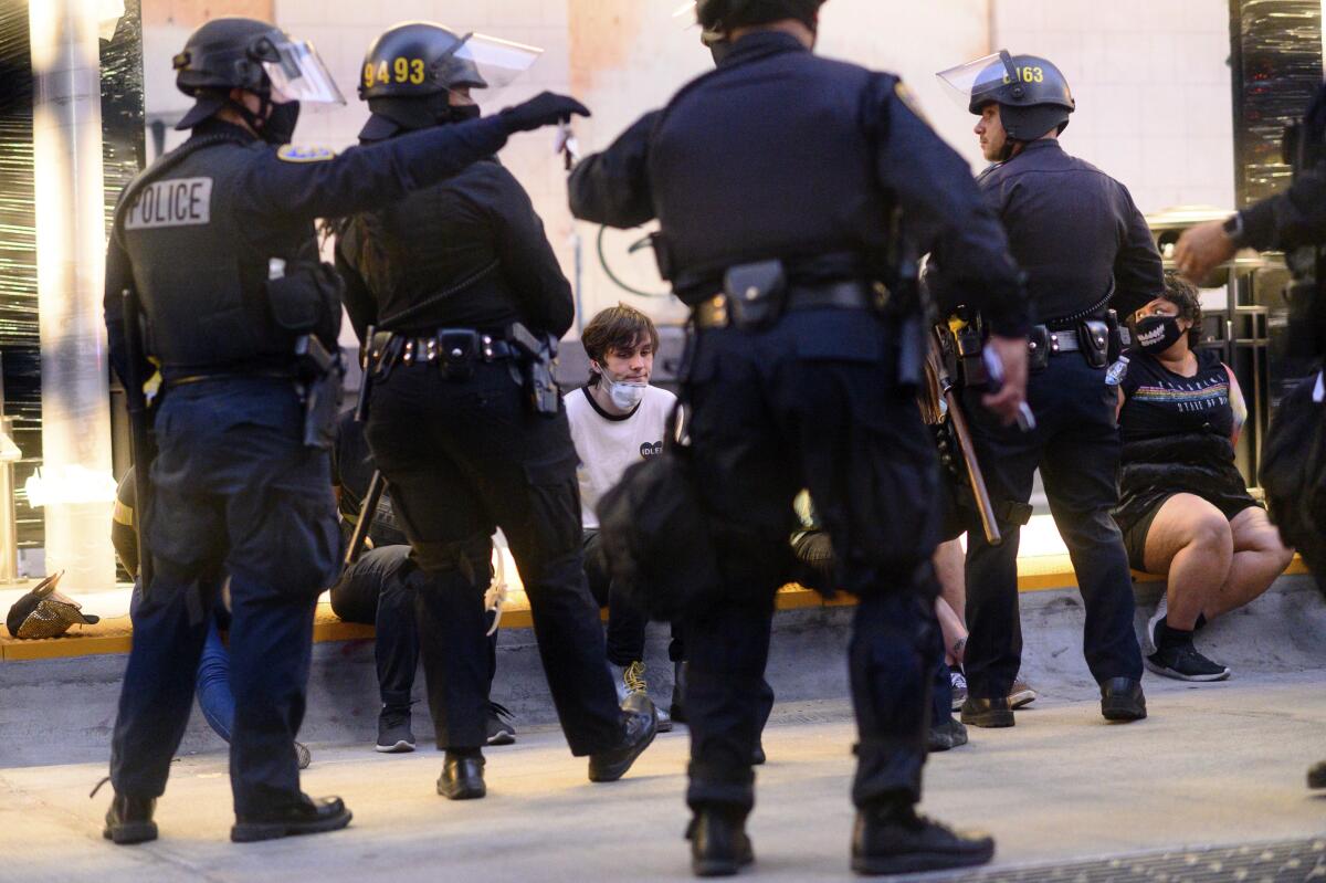 FILE - Police officers detain demonstrators in Oakland, Calif., on June 1, 2020. Alameda County has agreed to ban rubber bullets, bean bags and less-lethal munitions for crowd control as part of a settlement with two protesters who sued after being injured by rubber bullets fired by sheriff's deputies during 2020 protests in Oakland against police brutality, the plaintiff's lawyer said Thursday, Sept. 1, 2022. (AP Photo/Noah Berger, File)