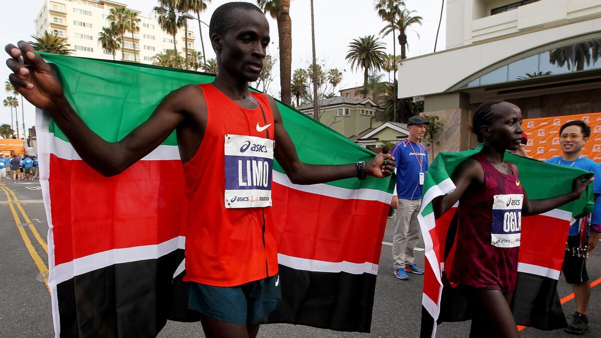 SANTA MONICA, CALIF. - MAR. 15, 2015. L.A. Marathon men's and women's elite division winners Daniel Limo. left, and Ogla Kimayao, both of Kenya, head to the medalist stanmd on Sunday, Mar. 15, 2015. (Luis Sinco/Los Angeles Times)