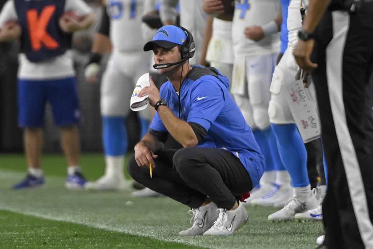  Chargers coach Brandon Staley kneels on the sideline.