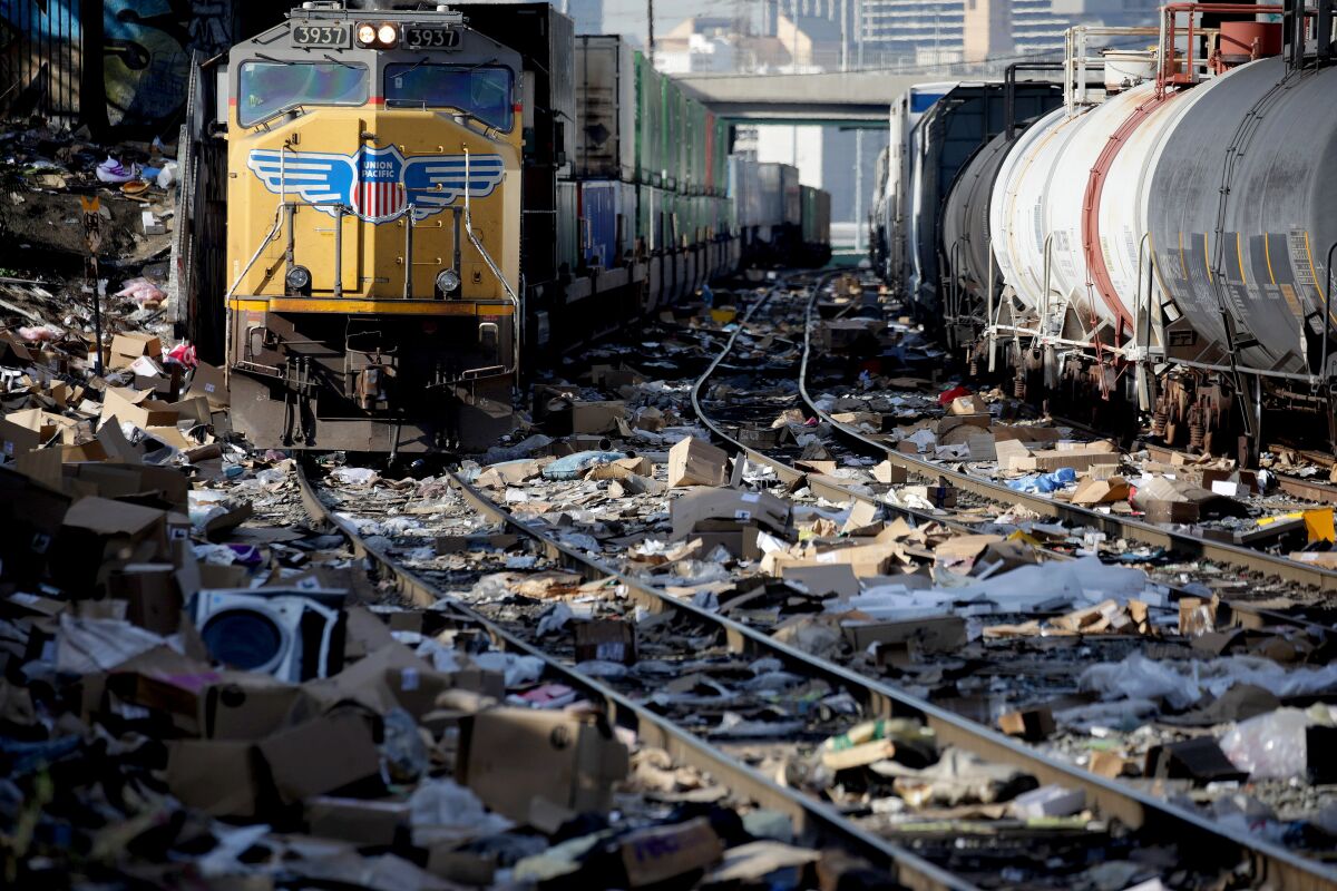 A train is seen on tracks covered with cardboard boxes and litter.