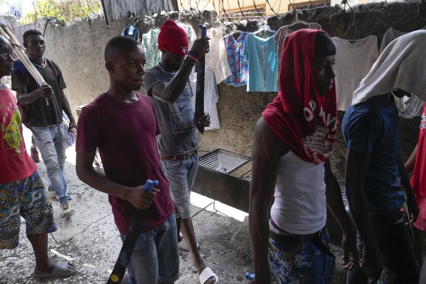 Men with machetes, part of "Bwa Kale," an initiative to resist gangs from getting control of their neighborhood, walk in the Delma district of Port-au-Prince, Haiti, Sunday, May 28, 2023. (AP Photo/Ariana Cubillos)
