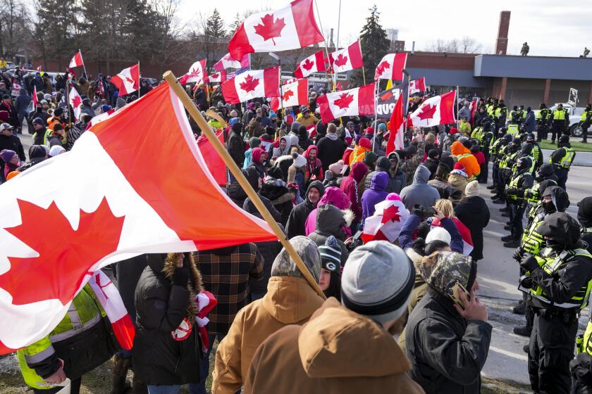 Police officers hold a line as protesters against COVID-19 restrictions march in Windsor, Ont., Saturday, Feb. 12, 2022. The demonstrations at the Ambassador Bridge, downtown Ottawa and elsewhere have targeted vaccine mandates and other coronavirus restrictions and vented fury toward Prime Minister Justin Trudeau, who has called the protesters a “fringe” of Canadian society. (Nathan Denette/The Canadian Press via AP)