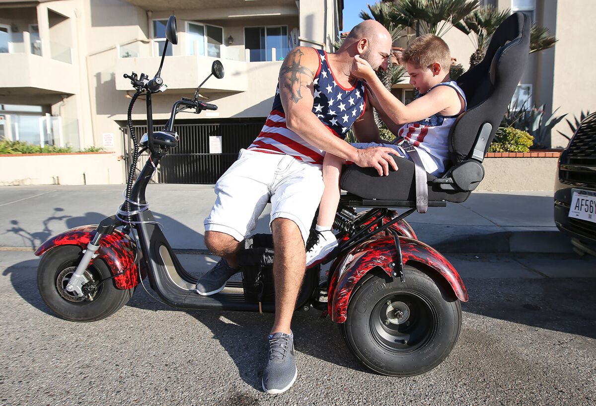 Jason David and son Jayden prepare for a trip on their new three-wheeled motorized scooter.