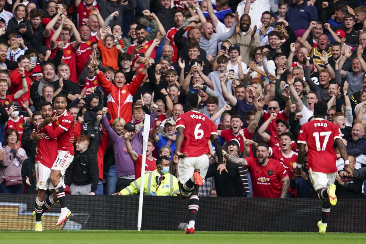 Manchester United's Bruno Fernandes, left, celebrates with teammates after scoring his team's first goal during the English Premier League soccer match between Manchester United and Leeds United at Old Trafford in Manchester, England, Saturday, Aug. 14, 2021. (AP Photo/Jon Super)