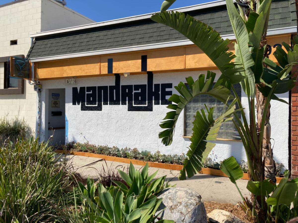 The exterior of a white building with the word Mandrake in black lettering