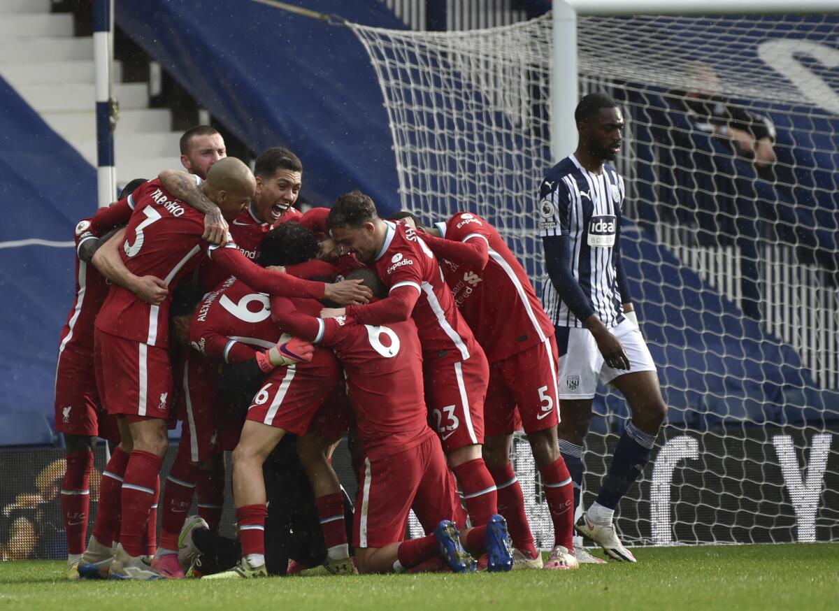 Liverpool's goalkeeper Alisson celebrates with teammates after scoring his side's second goal during the English Premier League soccer match between West Bromwich Albion and Liverpool at the Hawthorns stadium in West Bromwich, England, Sunday, May 16, 2021. (AP Photo/Rui Vieira, Pool)