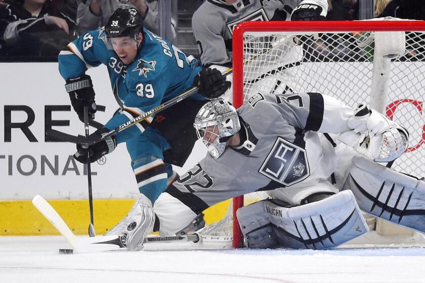 San Jose Sharks center Logan Couture, left, tries to move the puck past Kings goalie Jonathan Quick during the Kings' 4-1 win Saturday.