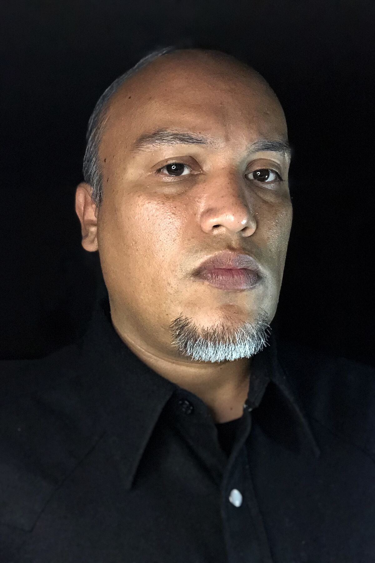 A portrait of Joel Garcia against a black background.