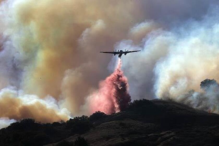 A plane drops fire retardant near the 91 Freeway in Anaheim Hills, where more than 12,500 people were ordered to evacuate as of Saturday night.