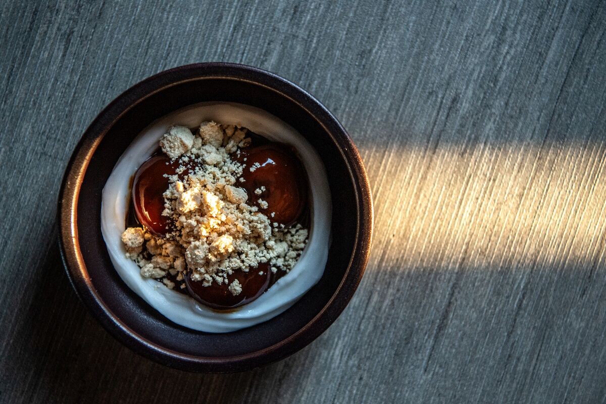 A bowl of dessert sits on a wooden table.