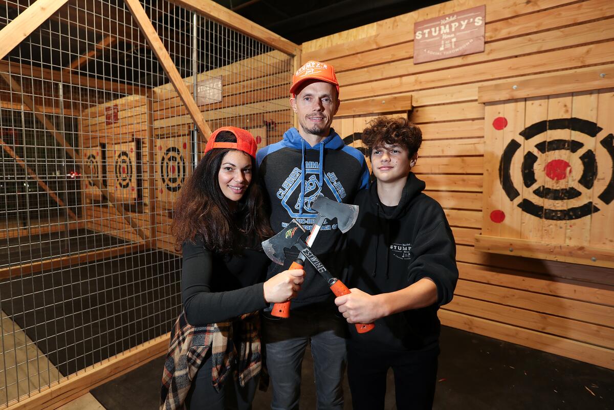 Owners Eric and Adriana LaShelle with son, Nikko, at one of the throw pits of Stumpy's Hatchet House in Huntington Beach.