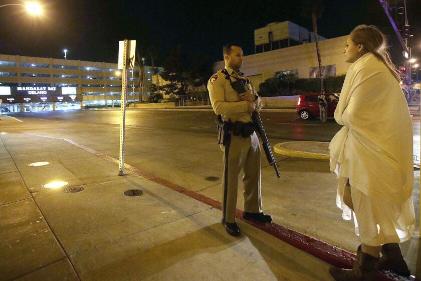 Mandatory Credit: Photo by PAUL BUCK/EPA-EFE/REX/Shutterstock (9106426a) A police officer stands guard on a closed street outside the Mandalay Bay hotel with a woman wrapped in a blanket near the scene of the Route 91 Harvest festival on Las Vegas Boulevard in Las Vegas, Nevada, USA, 02 October, 2017. Police reports indicate that a gunman firing from an upper floor in the Mandalay Bay hotel killed more than 50 people and injured more than 200 before police he was killed by police. Route 91 Harvest festival shooting, Las Vegas, USA - 02 Oct 2017 ** Usable by LA, CT and MoD ONLY **