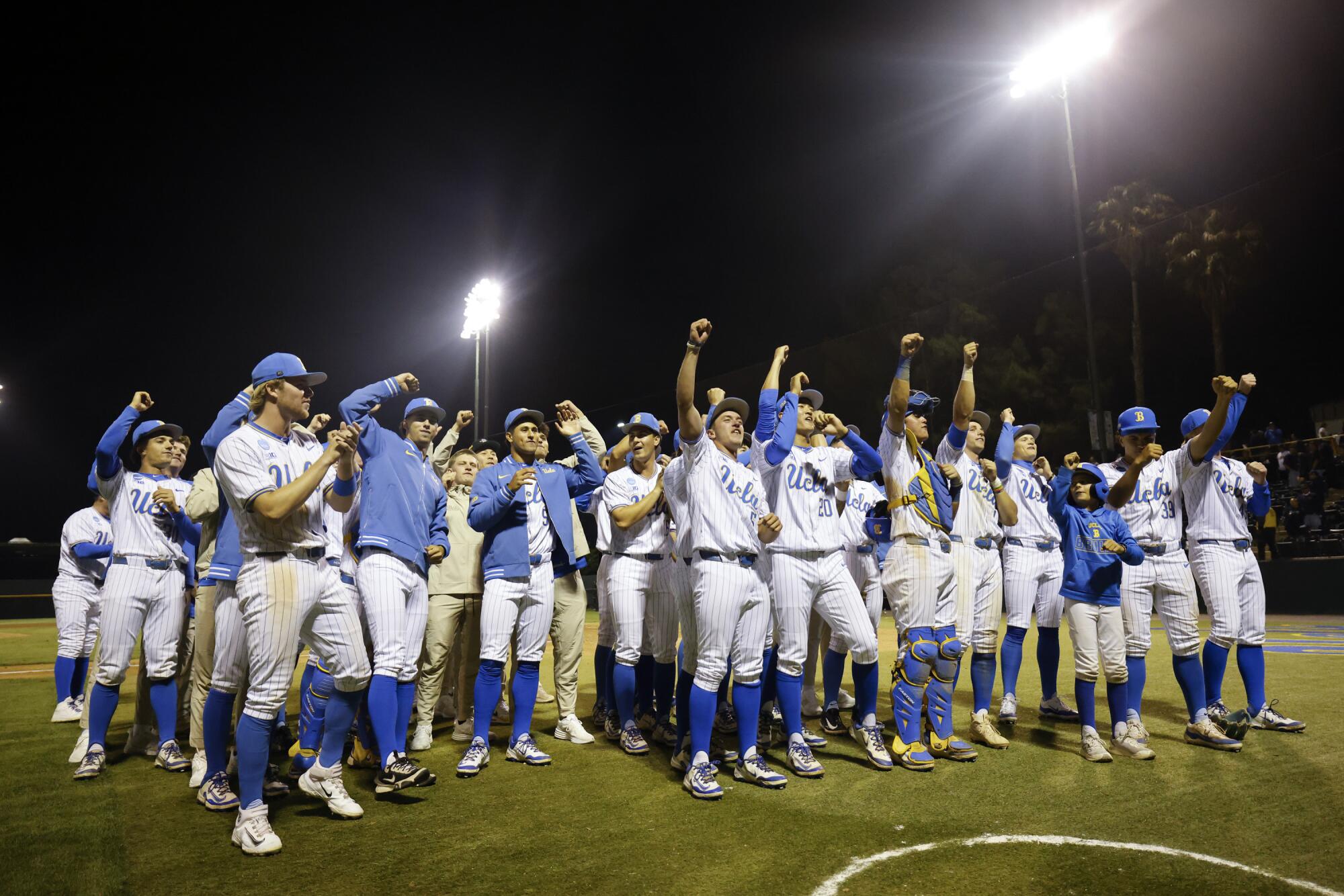 UCLA players and coaches line up cheering for a group photo.