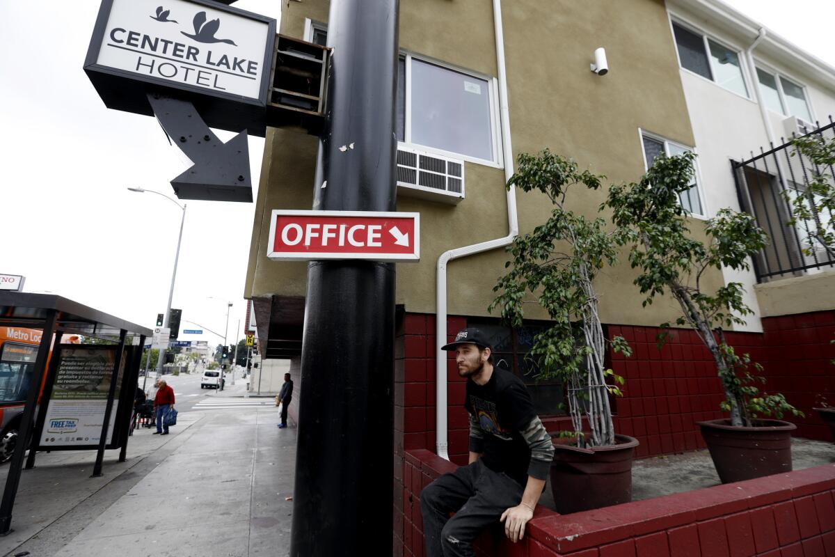 Peter Nelson waits for the bus in front of a building that has been known previously as the Royal Park Motel and Center Lake Hotel in Los Angeles.
