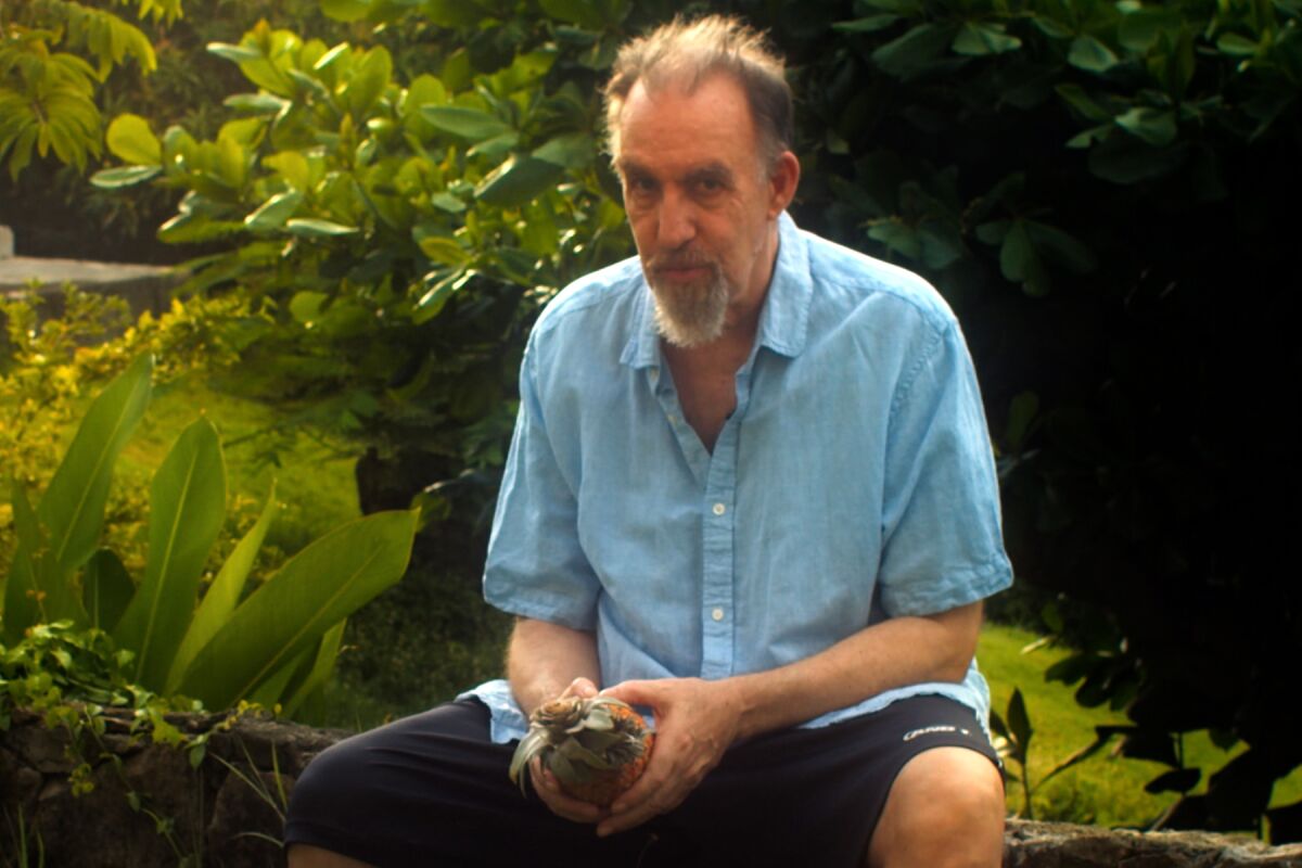 a man sits outside holding an object 