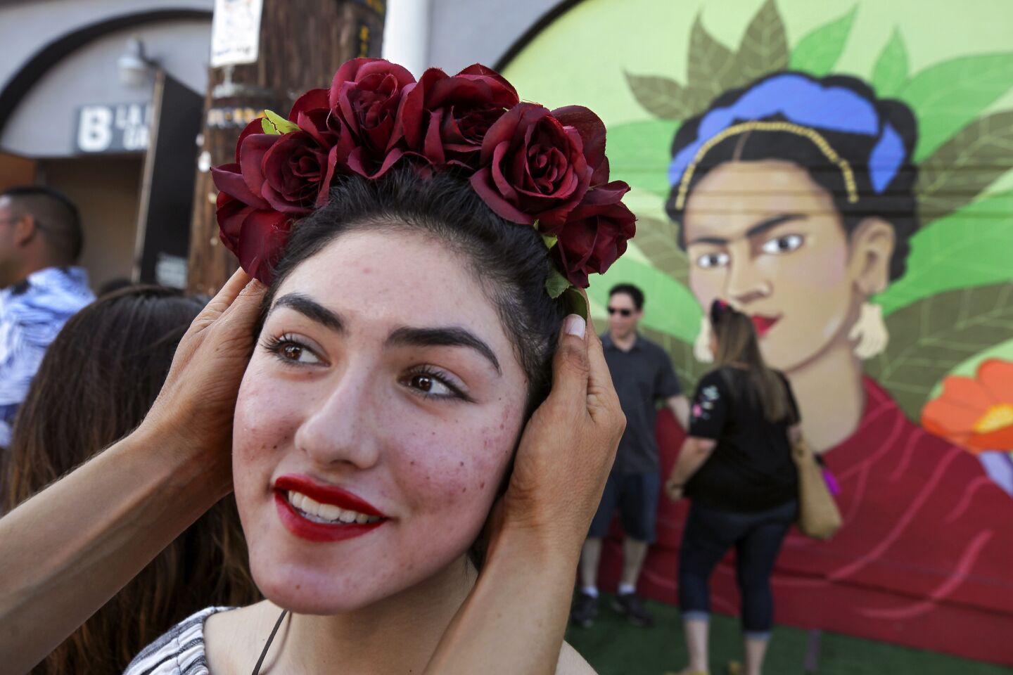 Frida Ramos, 16, stands in front of a large mural of Frida Kahlo, painted by artist and owner of the La Bodega Gallery Soni Lopez, as her mother Beatriz Ramos adjusts her Frida Kahlo style of flower crown while outside of the La Bodega Gallery during the 5th annual Friducha, a festival celebrating Mexican artist Frida Kahlo in Barrio Logan on Saturday, July 6, 2019 in San Diego, California.