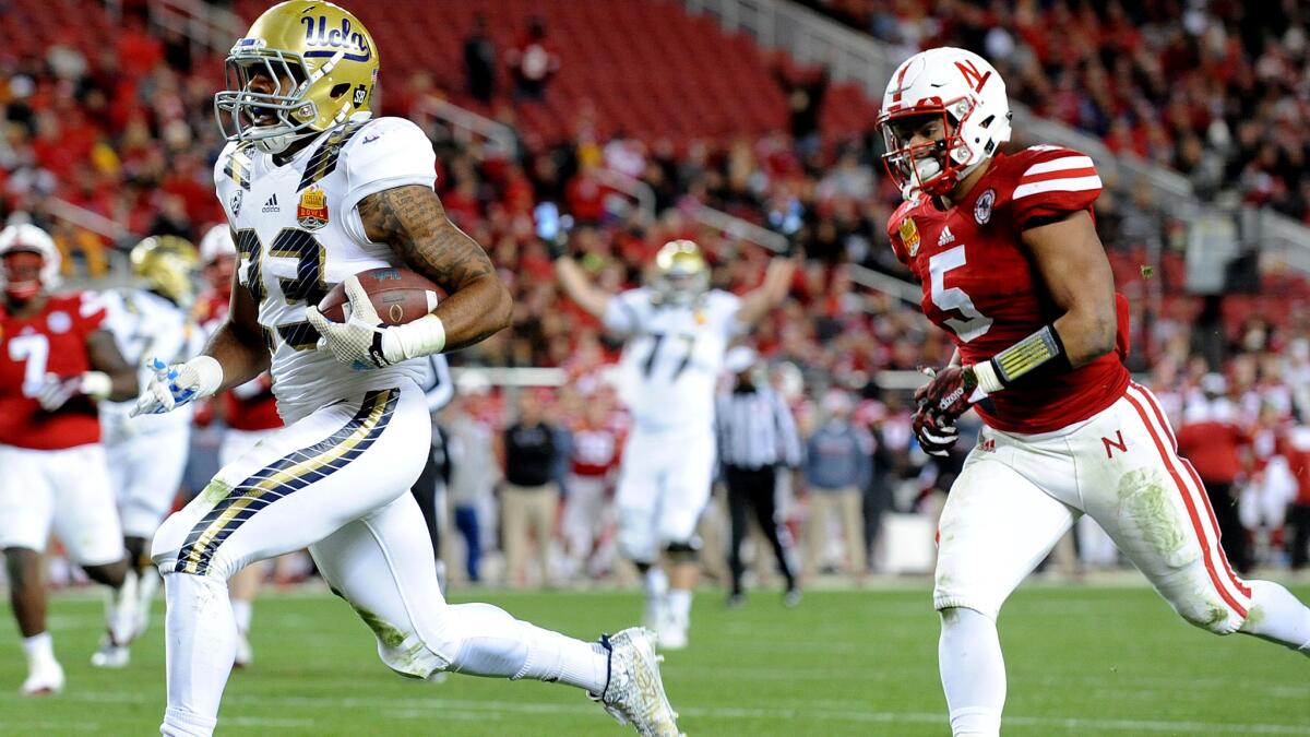 Bruins running back Nate Starks beats Cornhuskers linebacker Dedrick Young on a 26-yard scoring pass play in the second quarter for a 21-7 lead.