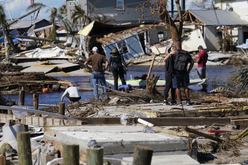 Gente de pie en el puente destruido a Pine Island mientras contemplan los daños causados por el huracán Ian en Matlacha, Florida, el domingo 2 de octubre de 2022. El único puente a la isla estaba muy dañado y sólo se podía acceder por mar o aire. (AP Foto/Gerald Herbert)