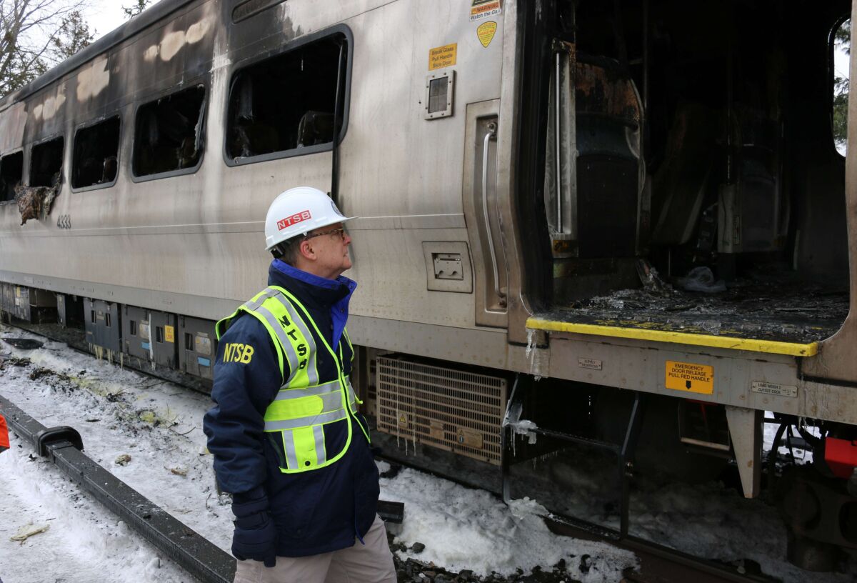 NTSB board member Robert Sumwalt studies a damaged rail car after Tuesday's deadly train trash in New York.