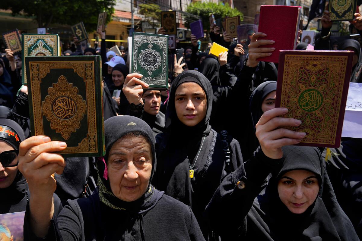 Women raise the Quran during a rally after Friday prayers in Lebanon. 