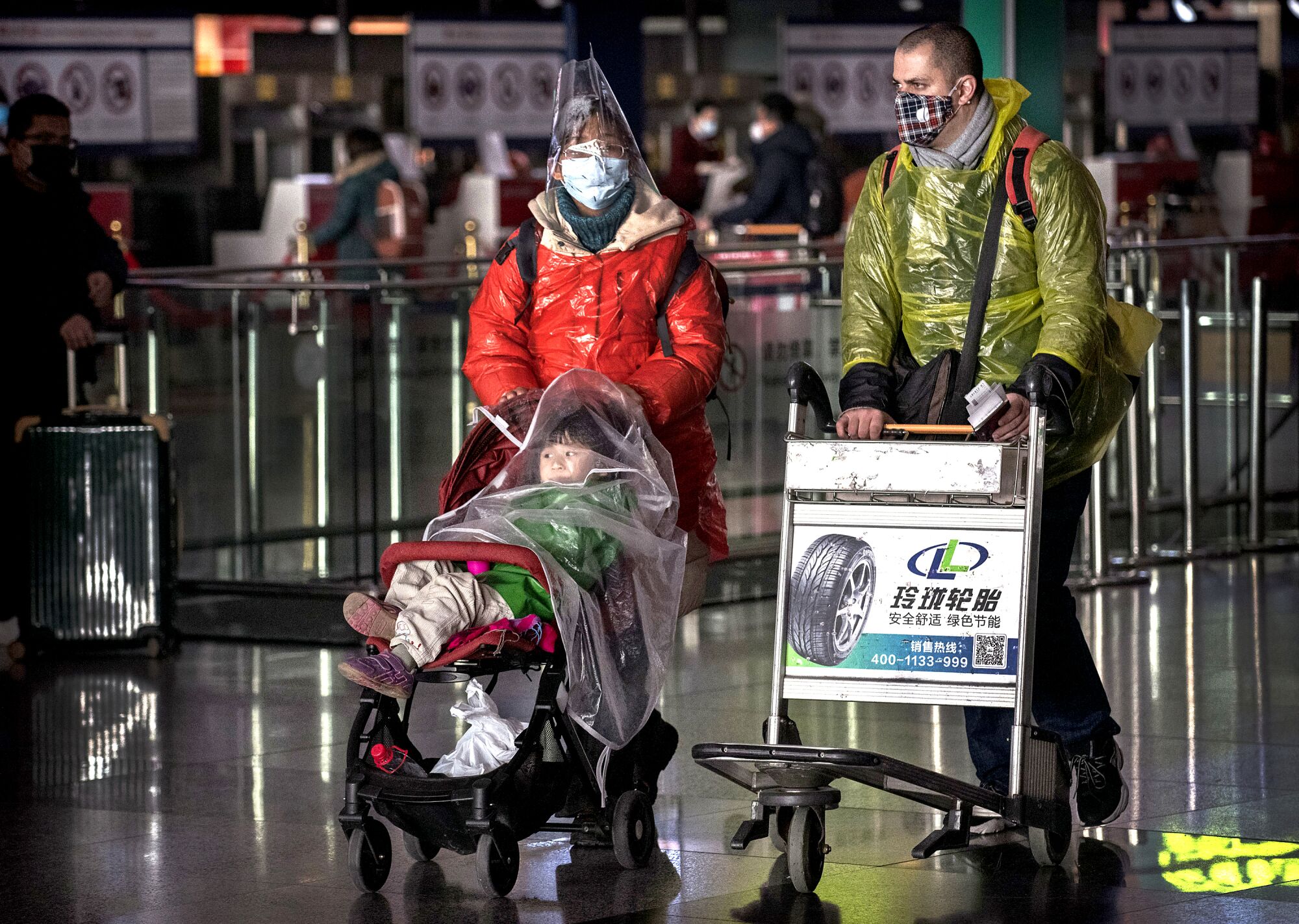 CHINA: A family wears masks and protective plastic covering after checking in to their flight at Beijing Capital International Airport.