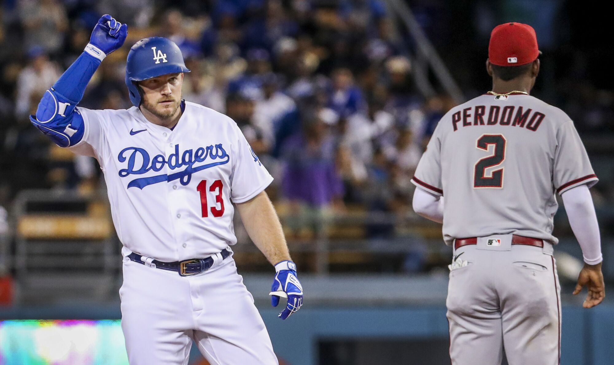 Dodgers Max Muncy taps his helmet as he celebrates hitting a double, as Diamondbacks shortstop Geraldo Perdomo walks away