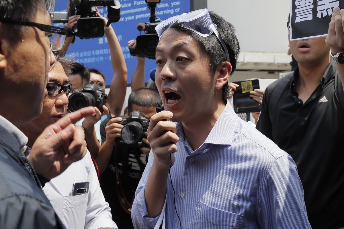 FILE - Hong Kong pro-democracy lawmaker Ted Hui, center, argues with pro-Beijing lawmaker Junius Ho, left, during a demonstration in Hong Kong Aug. 12, 2019. Hui was sentenced to 3 1/2 years in jail for criminal contempt after he skipped bail and fled overseas, missing trial for cases against him. (AP Photo/Kin Cheung, File)