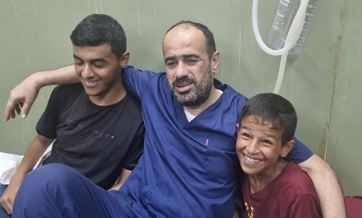 Mohammed Abu Selmia sits with his arms around two smiling boys.