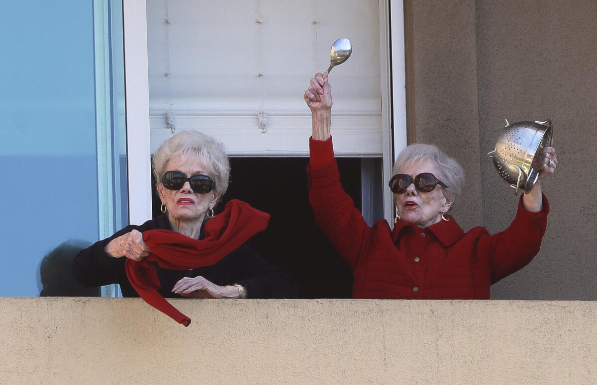 Jackie Voskamp, 91, waves a scarf as her twin sister, Joyce Kriesmer, bangs a colander.