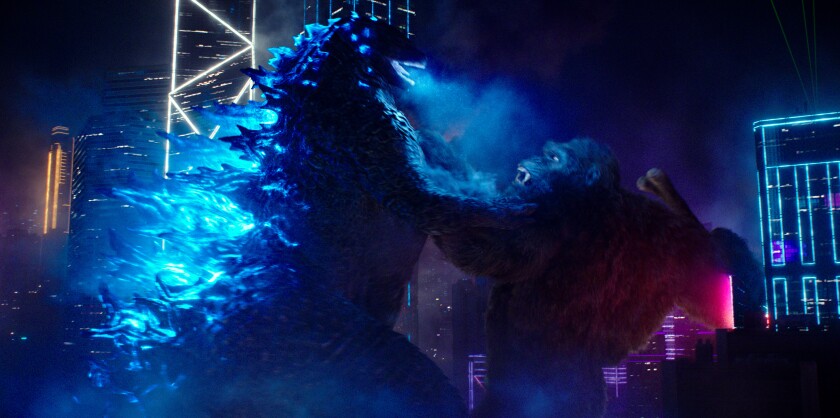 Gozilla and King Kong fight in the middle of the city.