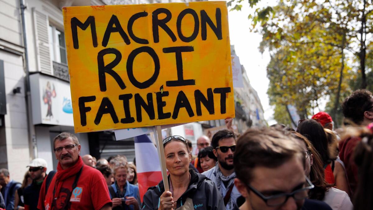 A demonstrator holds a placard referring to Emmanuel Macron as the slacker king during a protest in Paris on Sept. 23, 2017, over the French president's labor reforms.