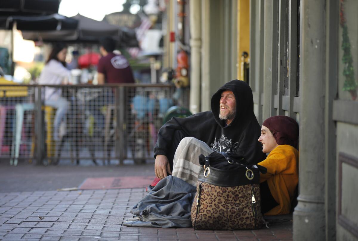 Homeless individuals sit on a street in Downtown San Diego in this 2019 file photo.