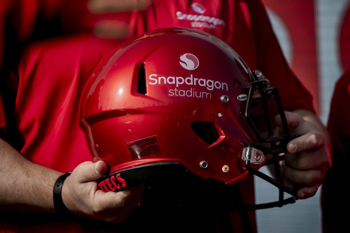 Cristiano Amon, chief executive officer of Qualcomm, holds a helmet with the stadium name on it.