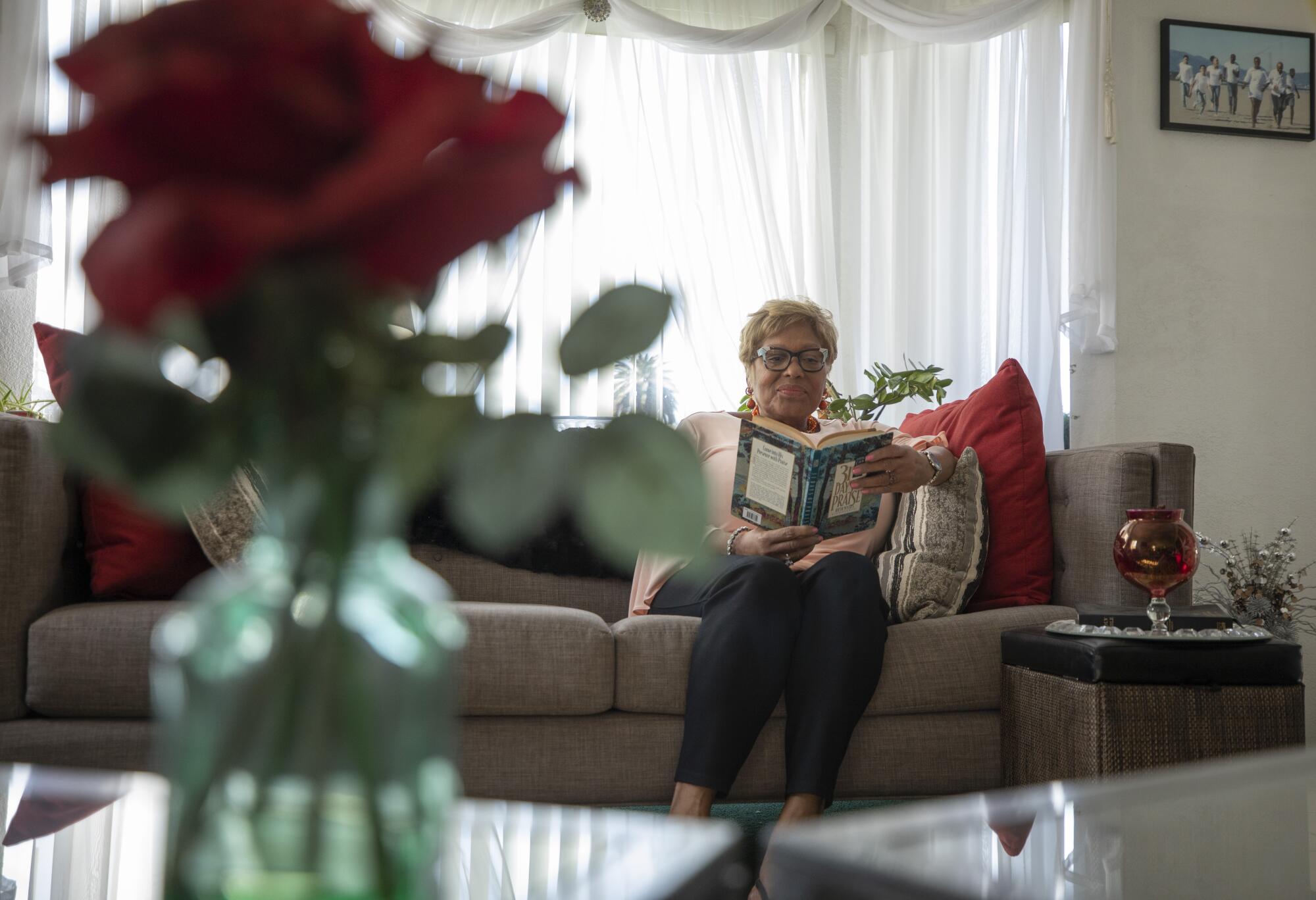 A woman on a couch reads a book.