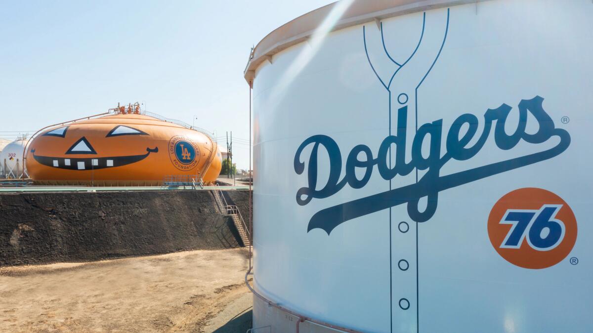 An oil tank made to look like a jack-o-lantern sits by an oil tank made to look like a Dodgers jersey.