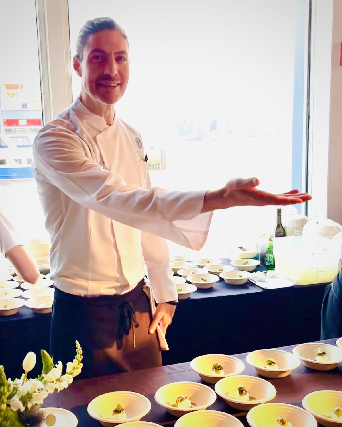 A chef gestures at plates spread before him.