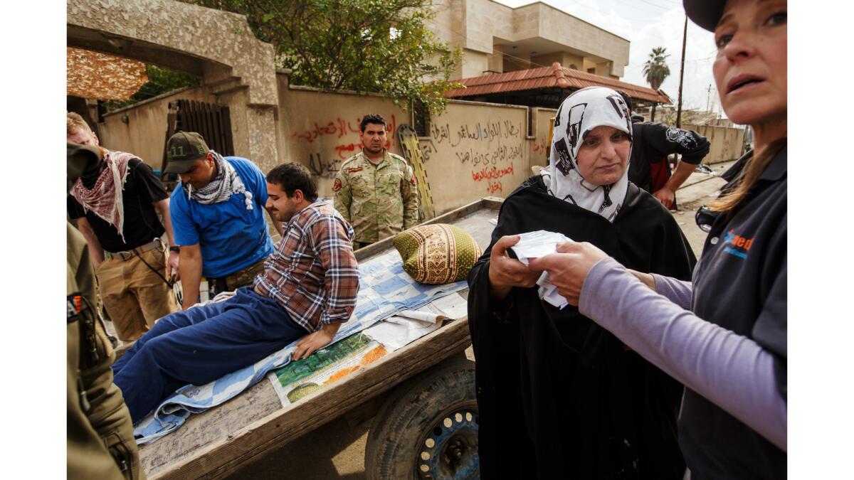 Kathy Bequary, right, NYC Medics executive director, inspects a medical prescription offered by an Iraqi woman as she requested treatment at a field clinic.