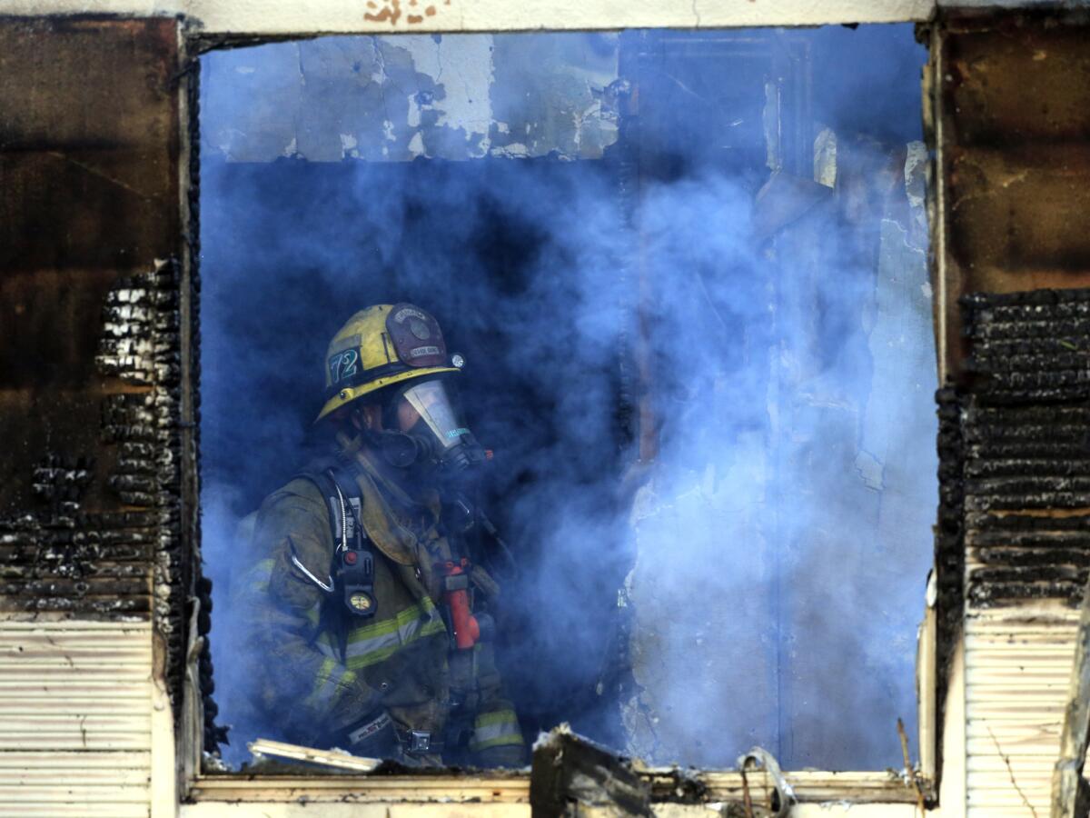 An Orange County Fire Authority firefighter surveys a fire-damaged home in Santa Ana in January.