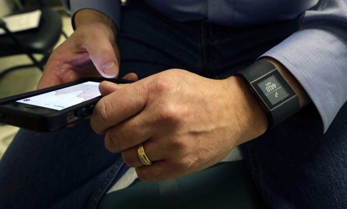 Gary Wilhelm, 51, looks at his medical data on a smartphone that is synchronized to a new Fitbit Surge on his wrist during an examination in Hackensack, N.J.