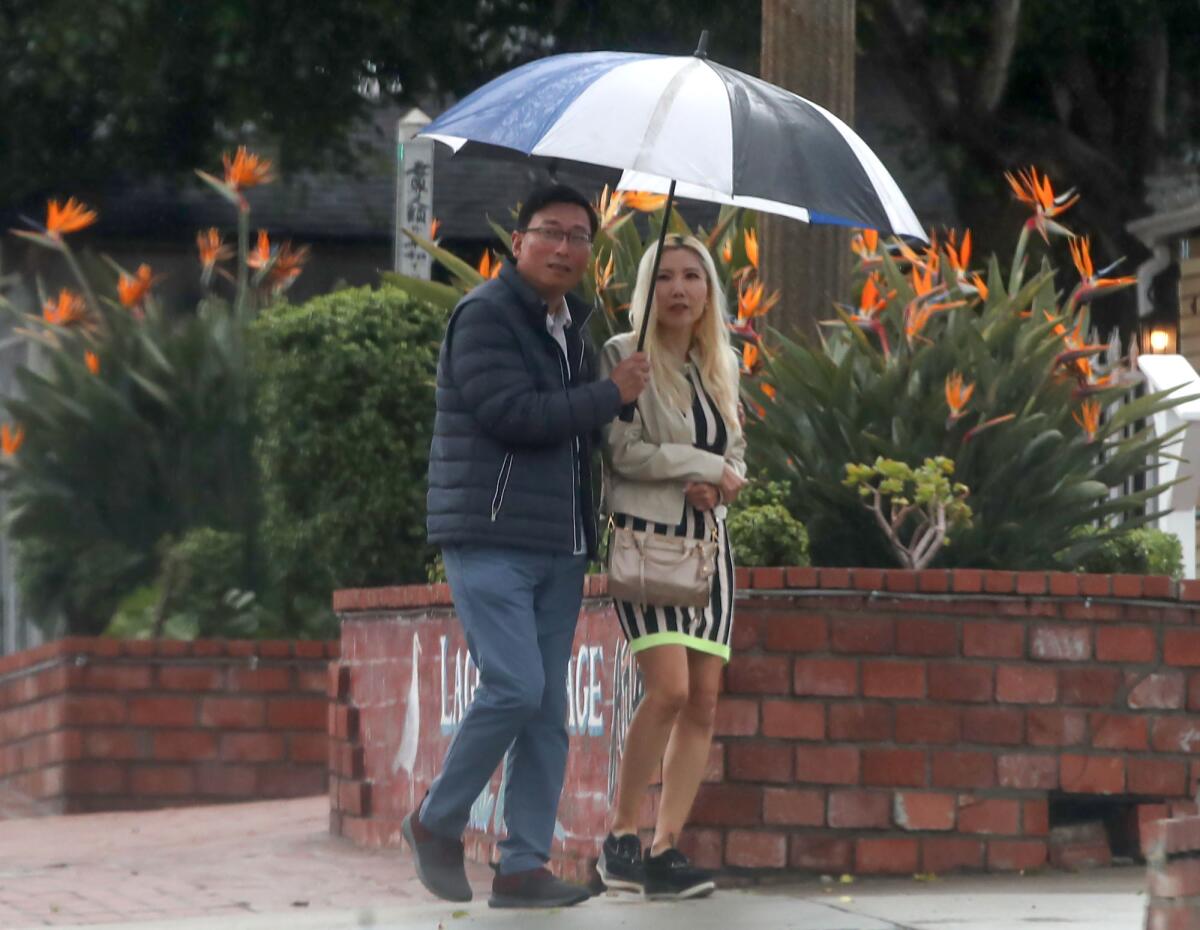 A couple share an umbrella as rain falls in downtown Laguna Beach on Thursday afternoon.