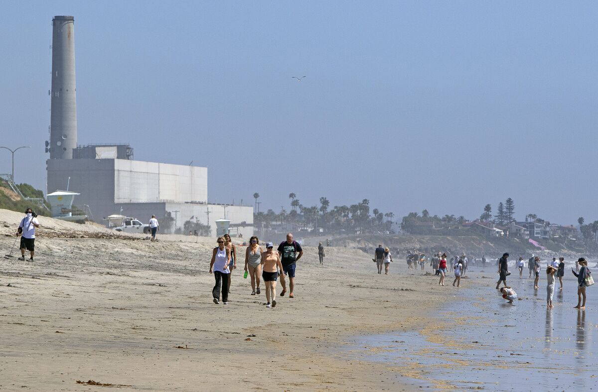 People stroll along the shore of Carlsbad State Beach after it re-opened Monday.