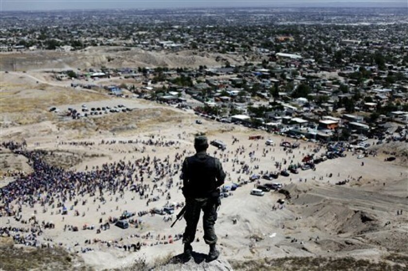 In this April 10, 2009 file photo, a soldier stands guard on the top of a hill as faithful commemorate Good Friday during Holy Week in Ciudad Juarez, Mexico. Killings by criminal gangs in the drug violence-wracked border city of Ciudad Juarez fell by 42 percent in the first six months of this year from the same period of 2011, Mexicoís army said Wednesday July 11, 2012. (AP Photo/Rodrigo Abd)