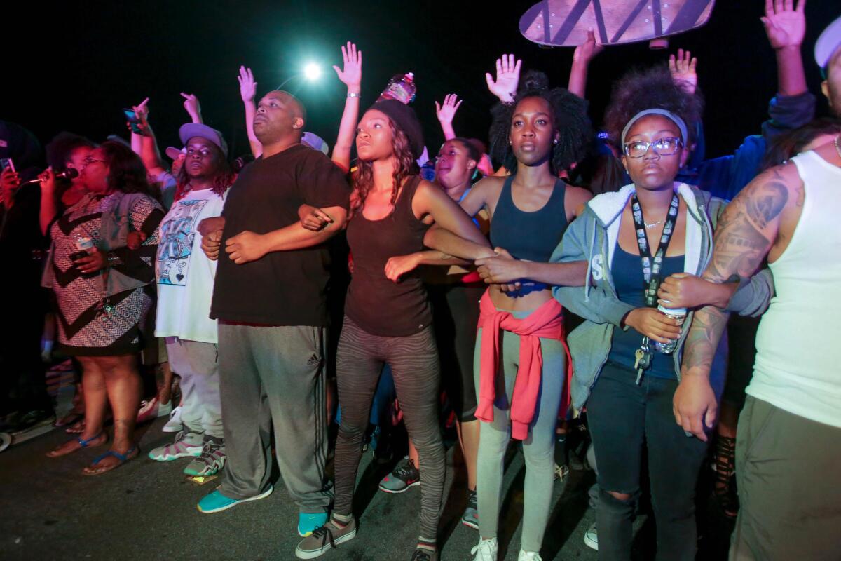 Protesters lock arms in front of a police line in El Cajon after the police shooting of Alfred Olango.