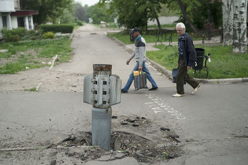 People walk past a piece of a rocket that landed in the Luhansk region of Ukraine.