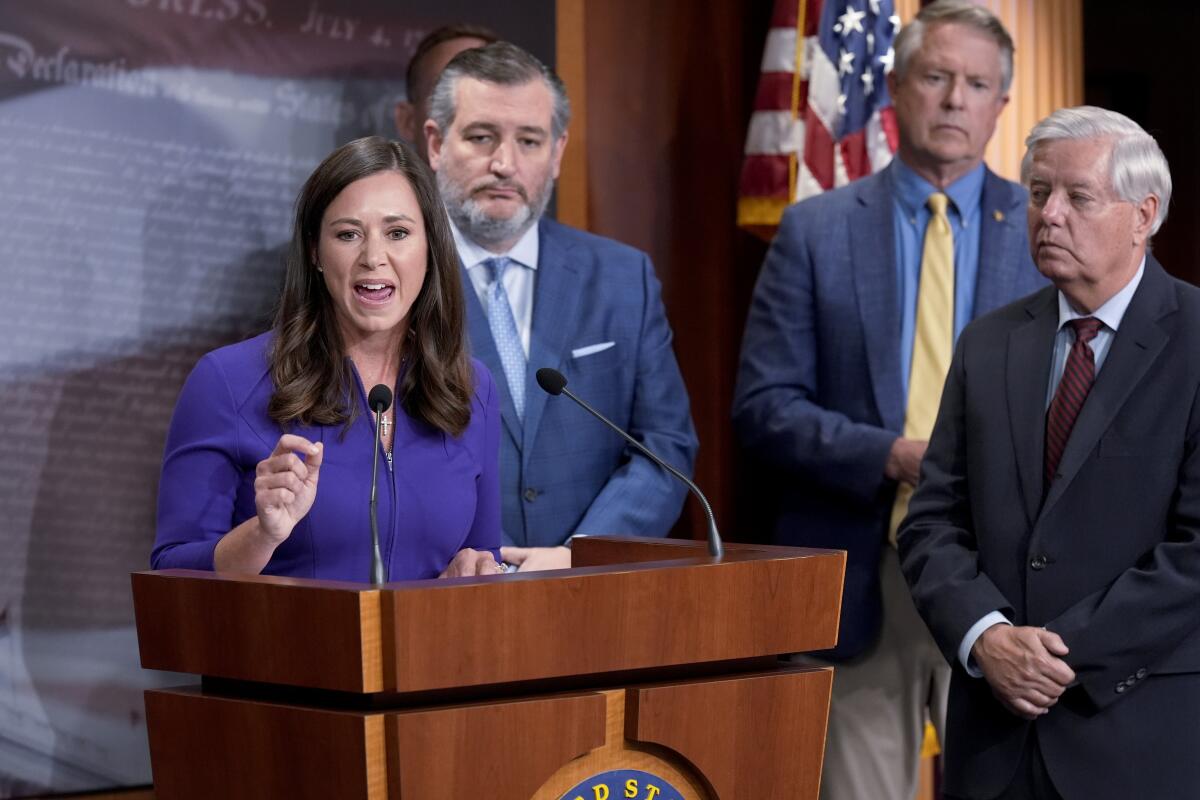 Sens. Katie Britt (left) and Ted Cruz, seen standing next to each other at a news conference.