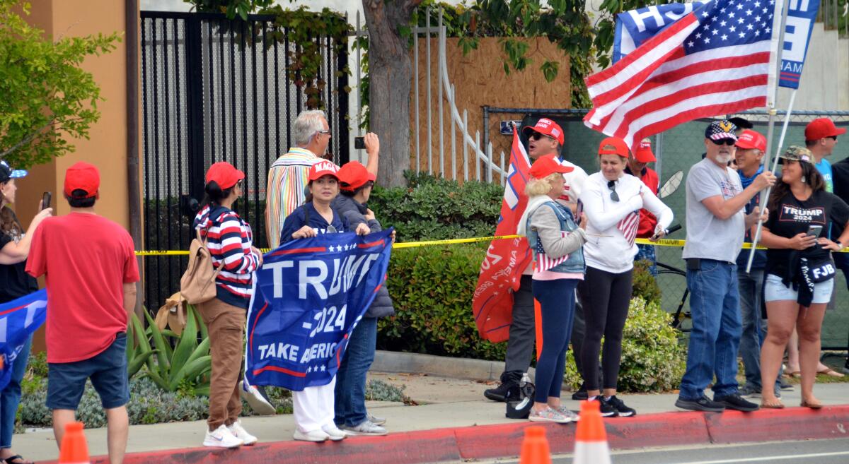 A man carrying a red Trump flag shouted at a man videotaping him on Bayside Drive during a Trump rally.