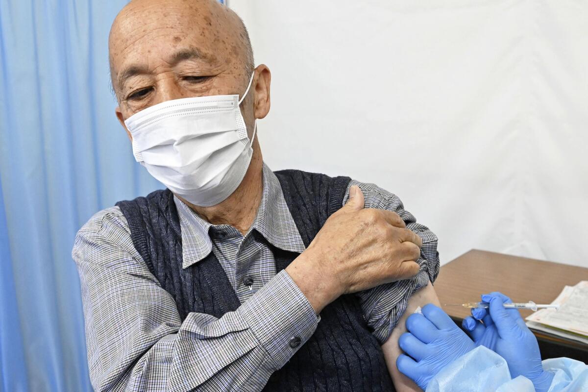 An elderly man receives his first dose of Pfizer's COVID-19 vaccine at Hachioji City Hall in Tokyo Monday, April 12, 2021. Japan started its vaccination drive with medical workers and expanded Monday to older residents, with the first shots being given in about 120 selected places around the country. (Kyodo News via AP)