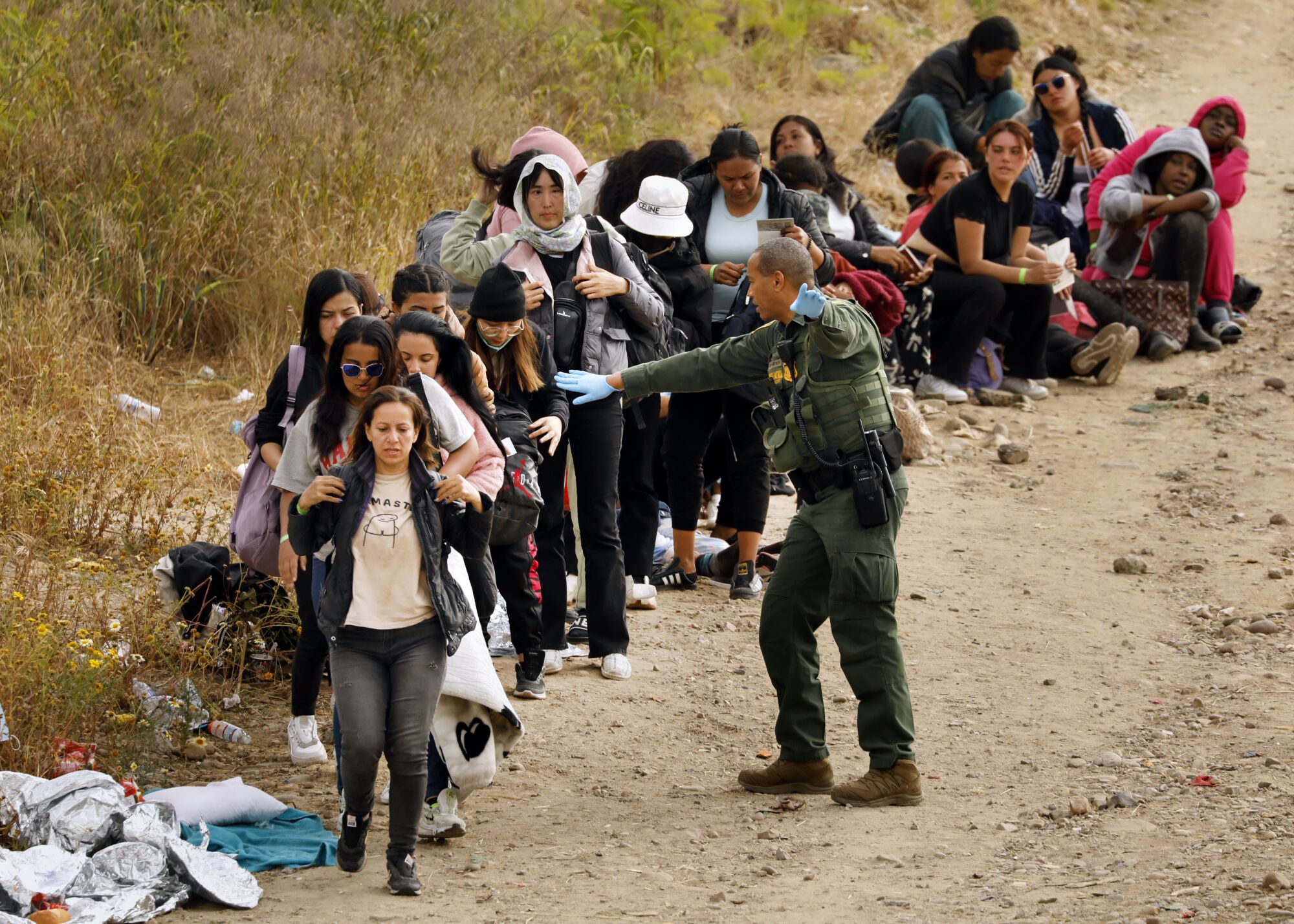 U.S. border patrol agents lead a group of women to vehicles headed to processing.