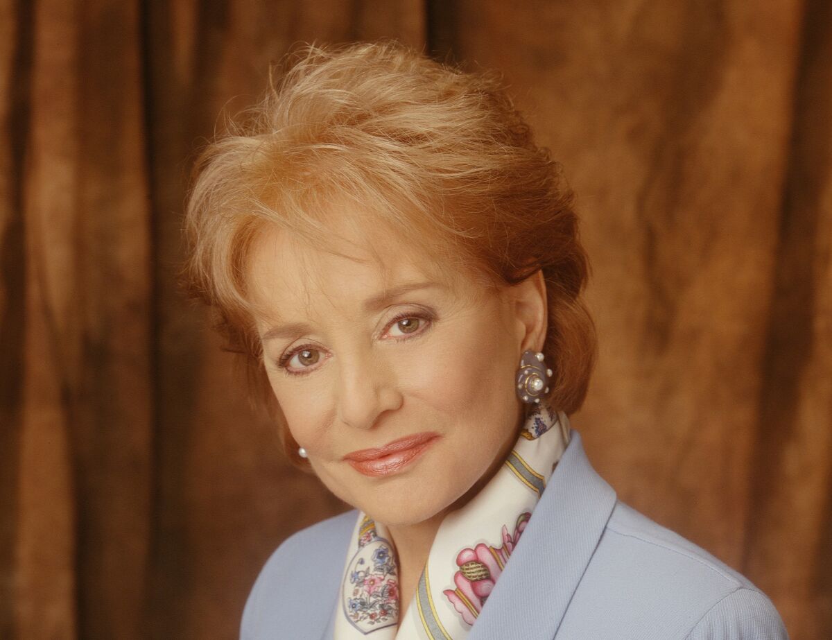 A smiling woman with short hair in a light blazer with a scarf around her neck.